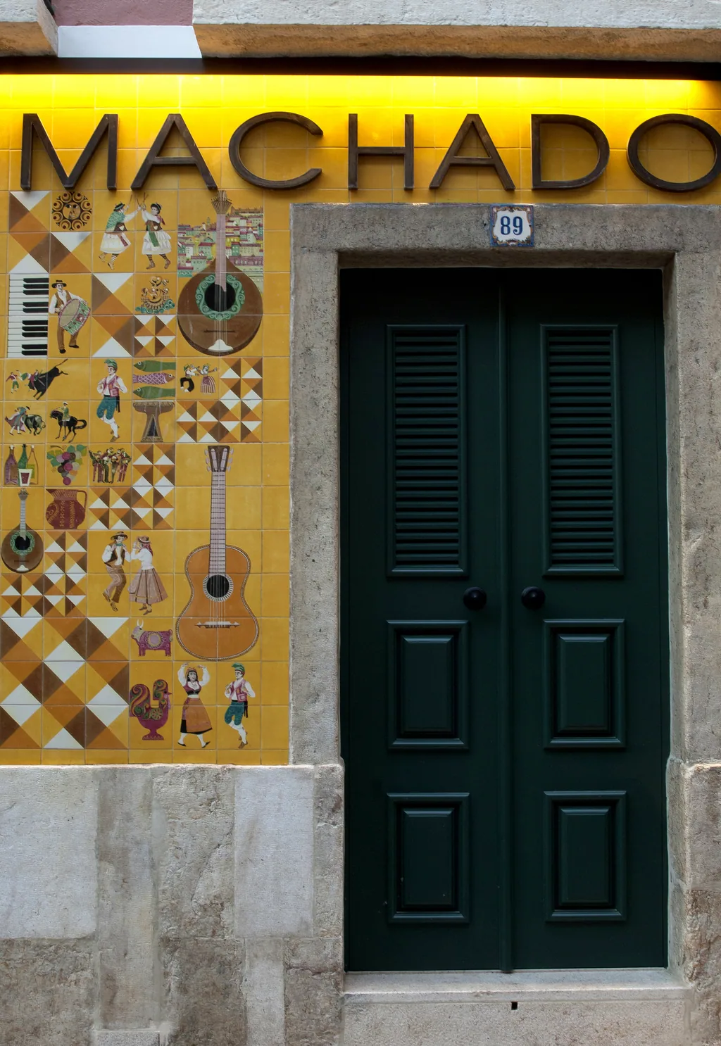 Porta verde da Adega Machado sob o nome em azulejos, na Rua do Norte
