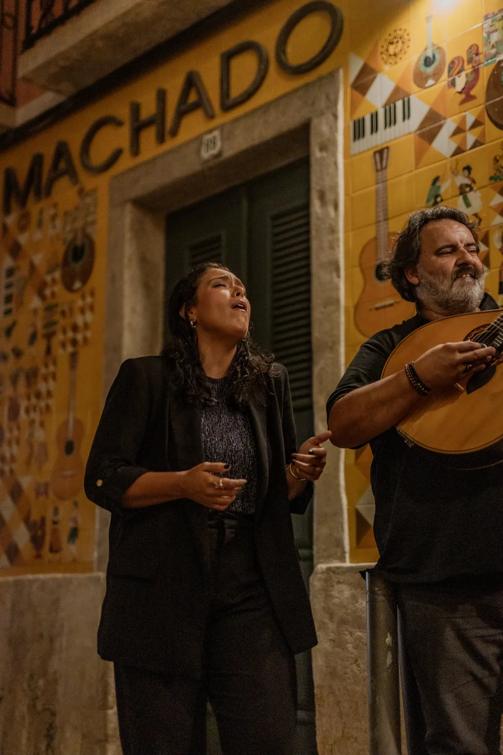 Fadista e chitarrista davanti alla facciata di azulejos dell'Adega Machado