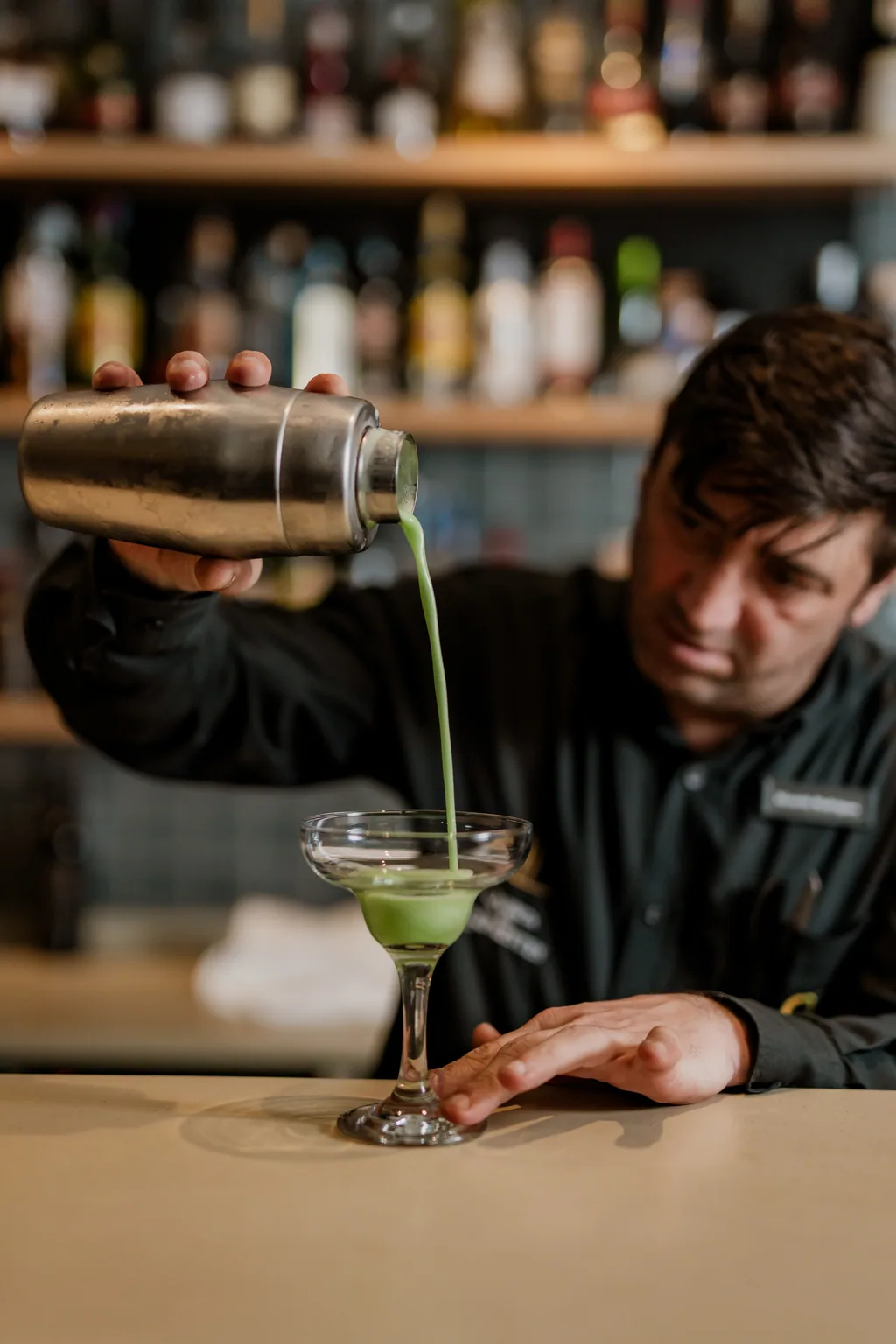 Barkeeper bereitet einen grünen Cocktail zu