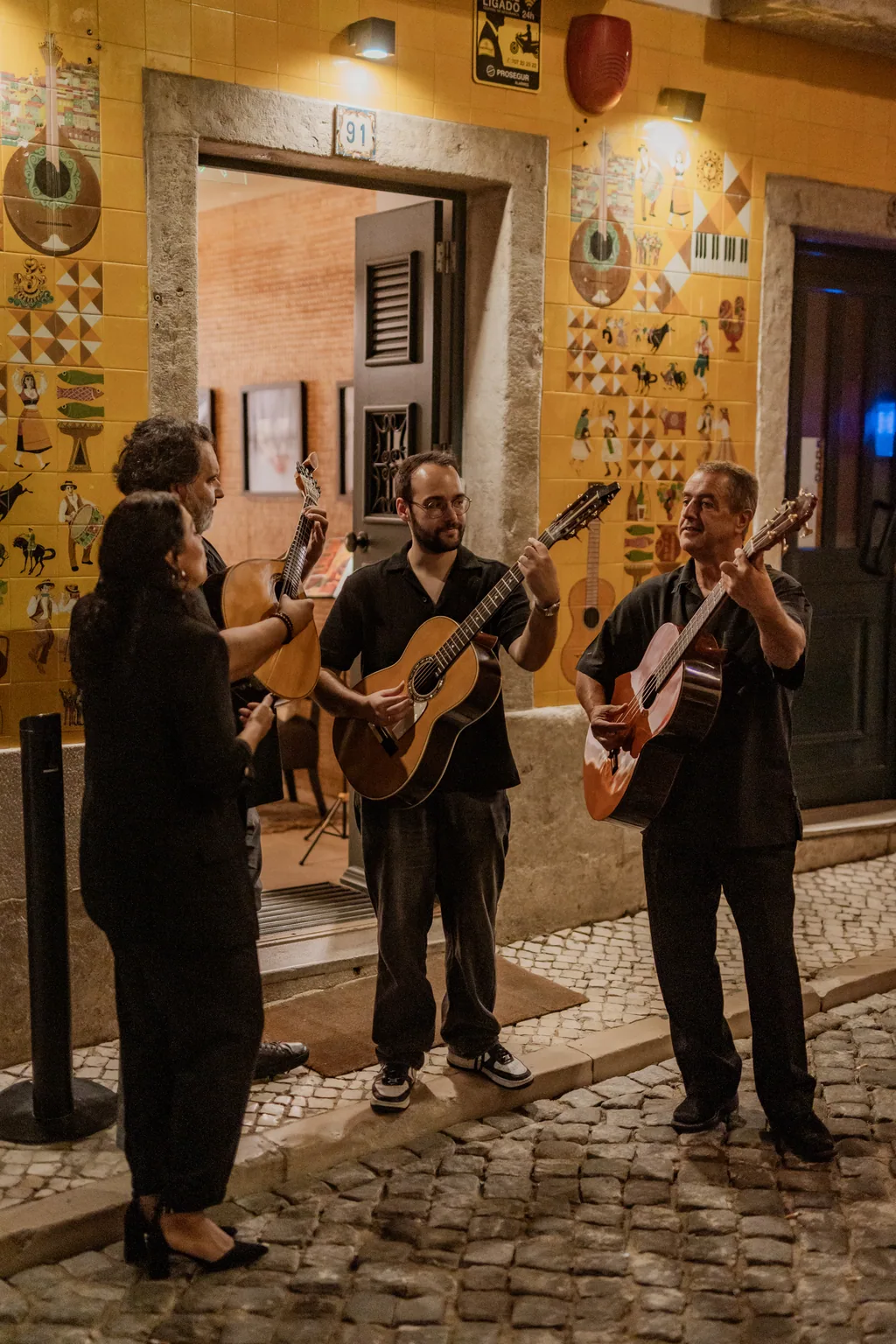 Três músicos junto à fachada azulejada da Adega Machado, no Bairro Alto