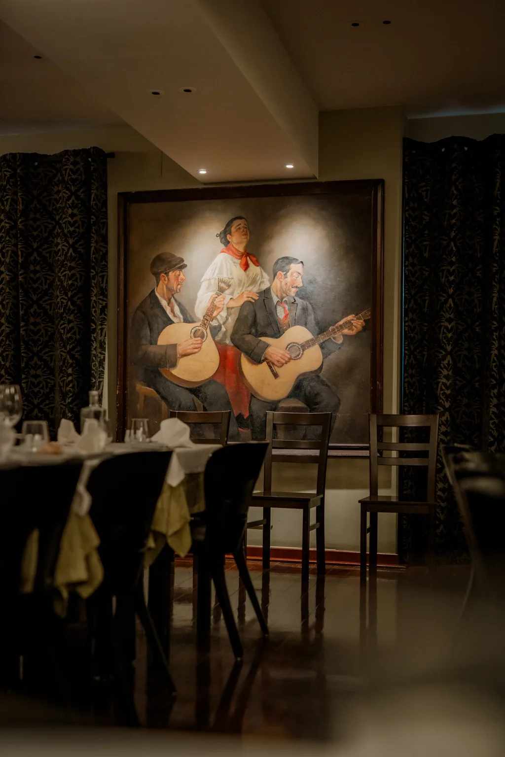 Pintura de três fadistas sobre a sala posta da Adega Machado