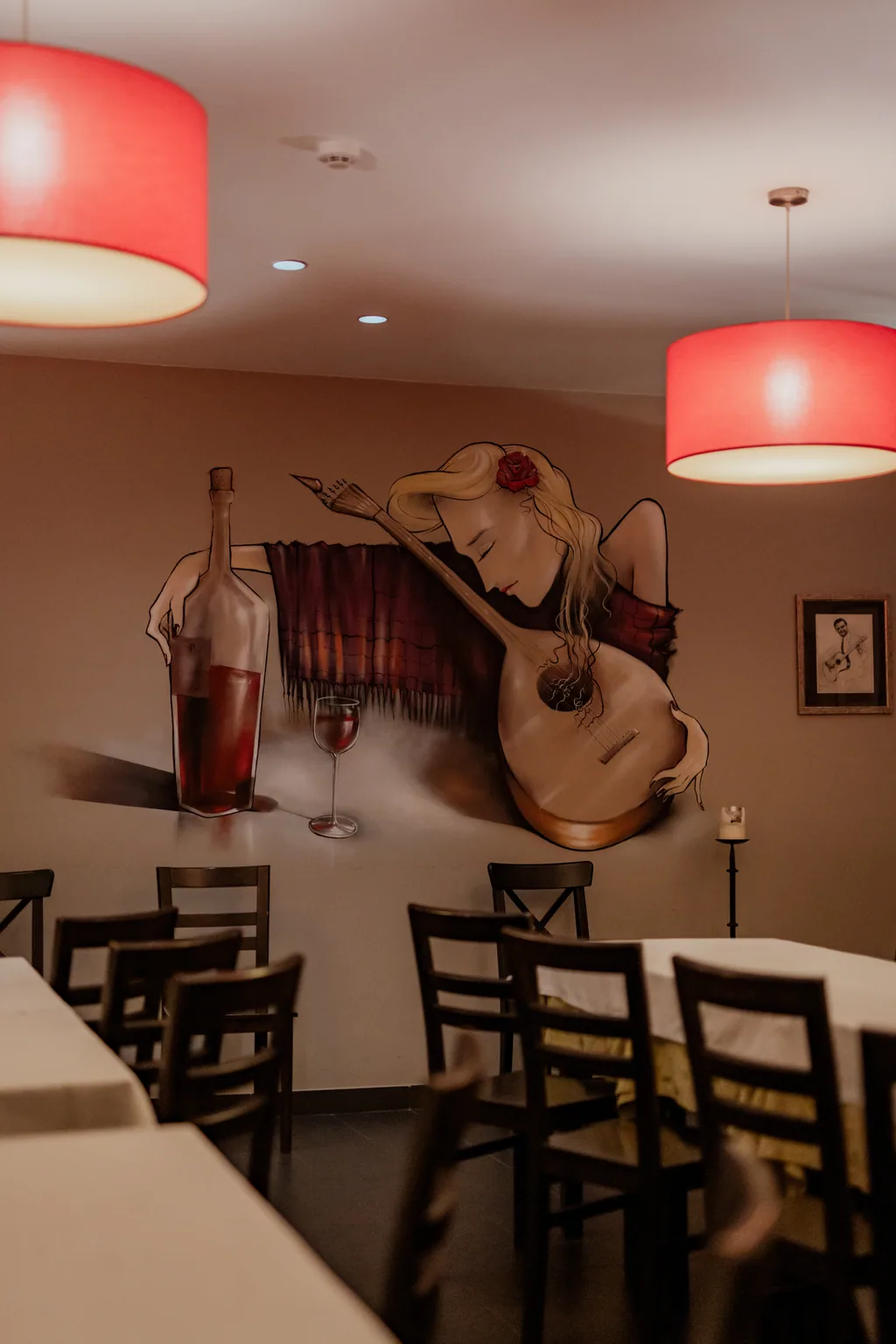 Sala com candeeiros vermelhos e mural de uma fadista com guitarra