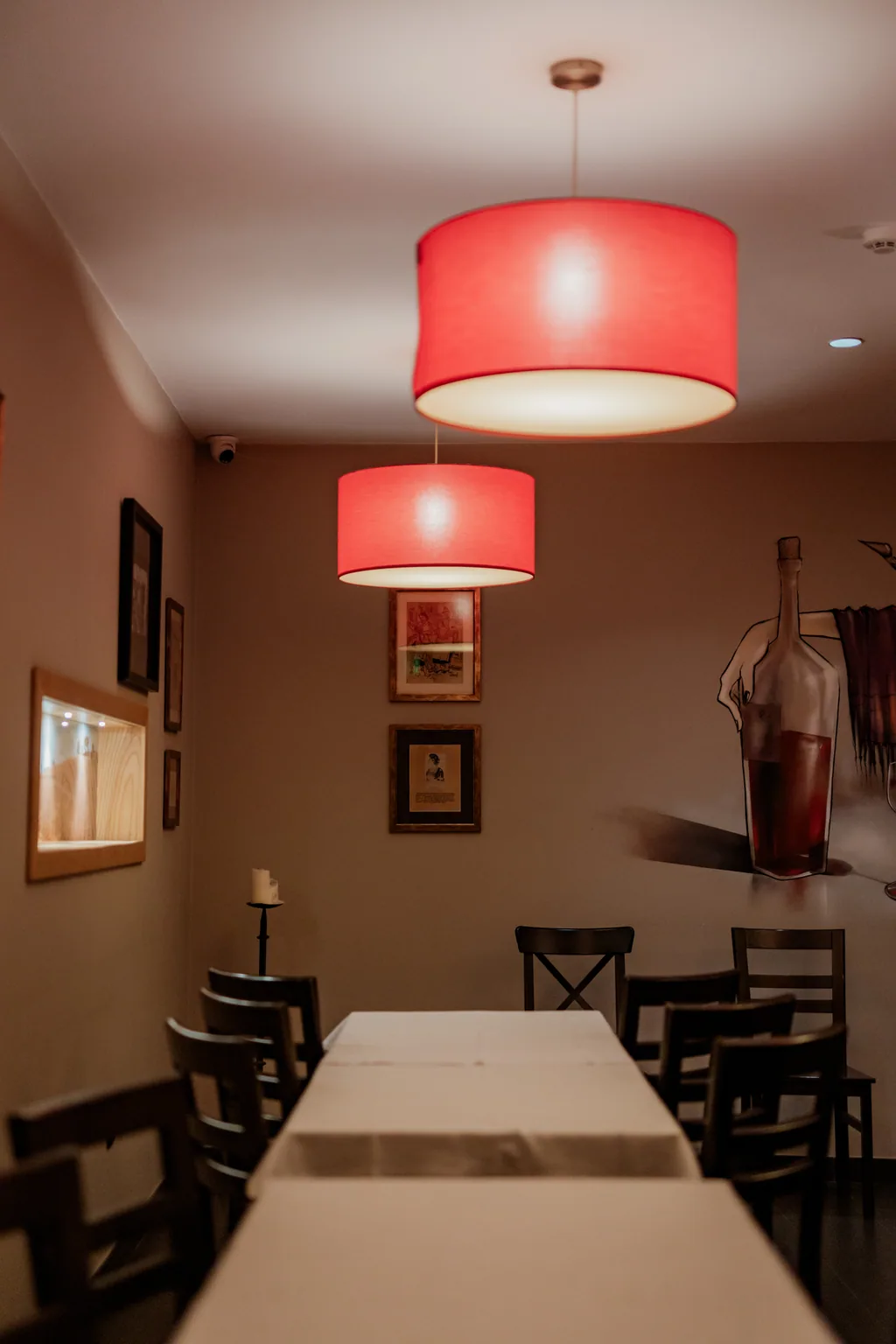 Long table laid under red lamps, set for a group