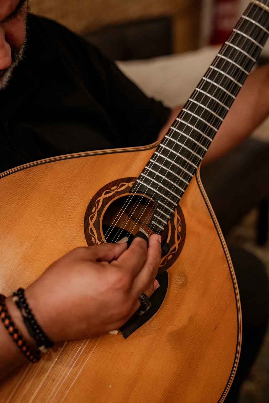 Detalhe da boca e do cavalete de uma guitarra portuguesa a ser tocada