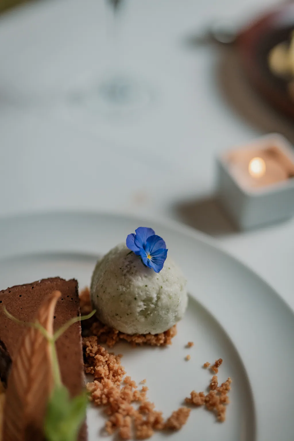Fatia de tarte de chocolate com quenelle de gelado e crumble, à luz da vela