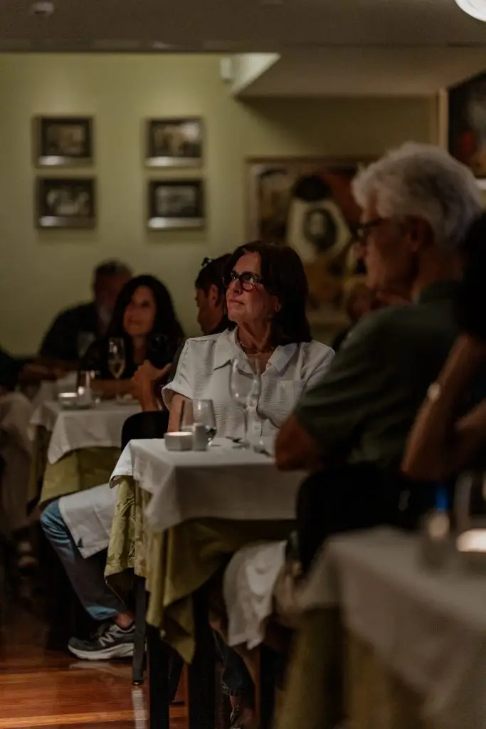 Sala de jantar da Adega Machado durante espectáculo de fado, com plateia atenta e mesas de toalha branca, Bairro Alto, Lisboa