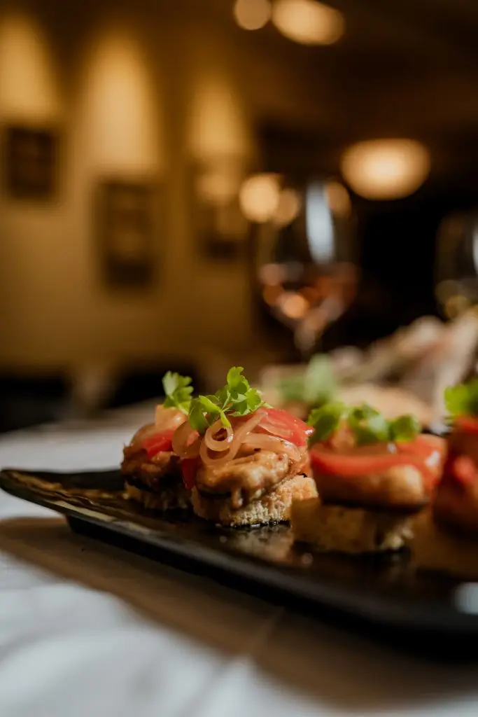 Petiscos sobre pão tostado em bandeja preta no bar da Adega Machado, Lisboa