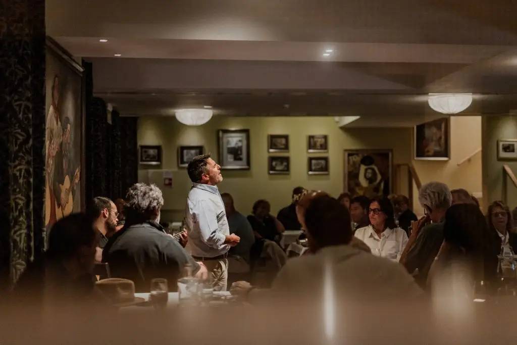 Fadista em primeiro plano com plateia atenta na sala da Adega Machado durante espectáculo de fado, Lisboa
