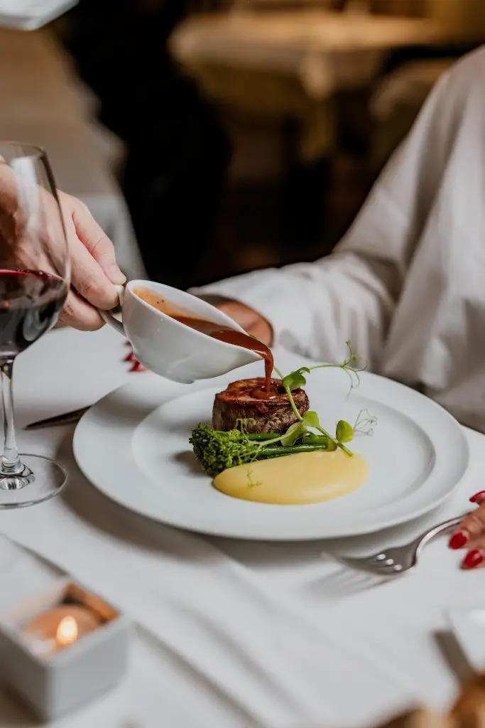 Tornedó de novilho com puré e brócolos a ser servido com molho na Adega Machado, Lisboa