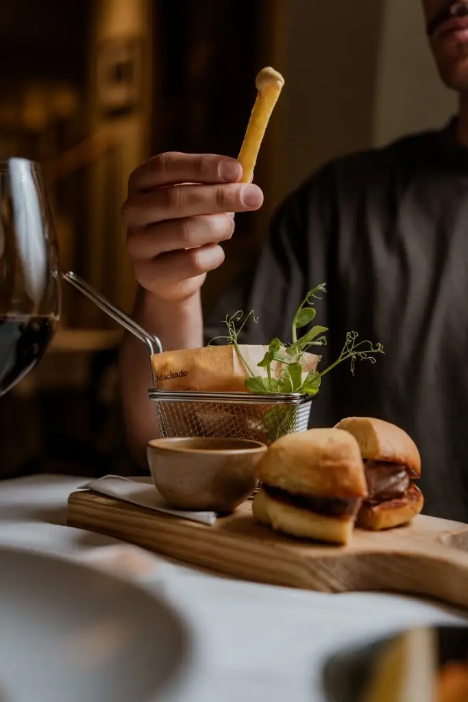 Mini hambúrgueres servidos com batatas fritas em cesta na Adega Machado, Lisboa