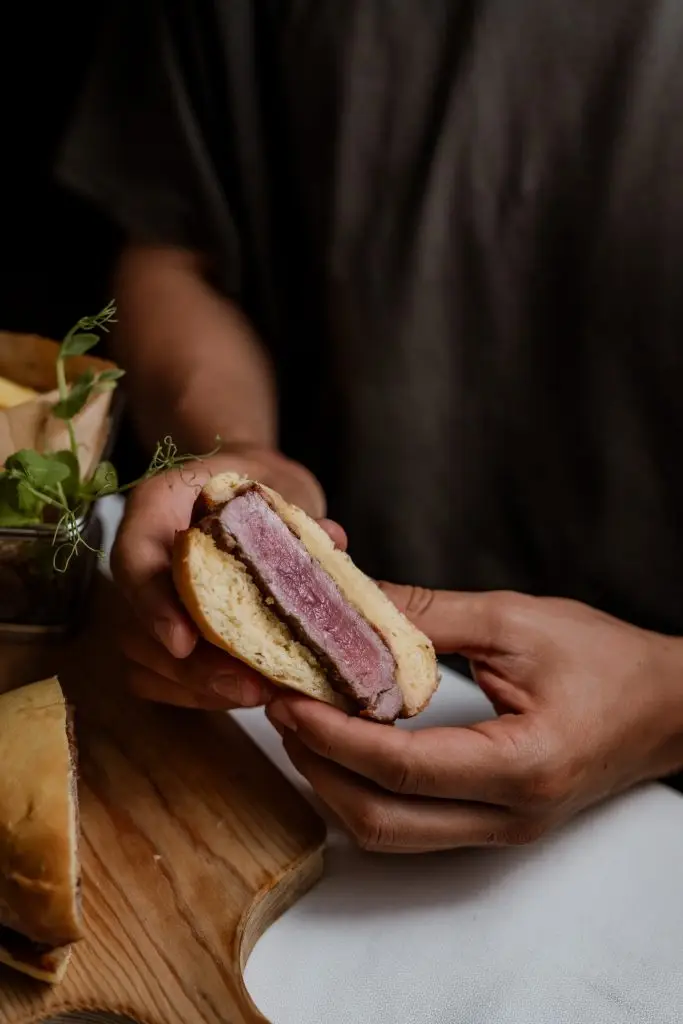 Prego no pão cortado ao meio mostrando bife e molho na Adega Machado, Lisboa