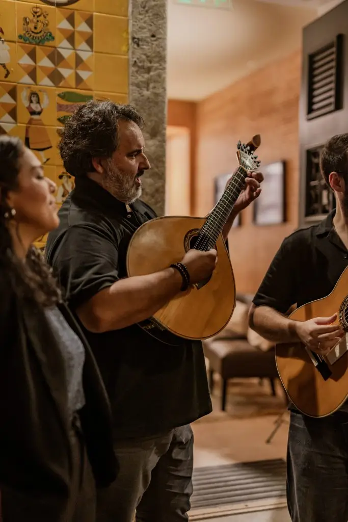 Fadista em perfil canta na Adega Machado com luz suave e ambiente característico de casa de fado lisboeta