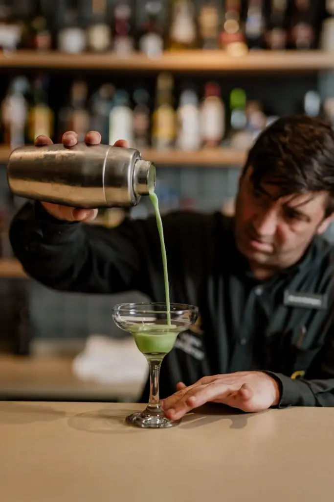 Bartender prepara cocktail verde com shaker no bar da Adega Machado, Lisboa